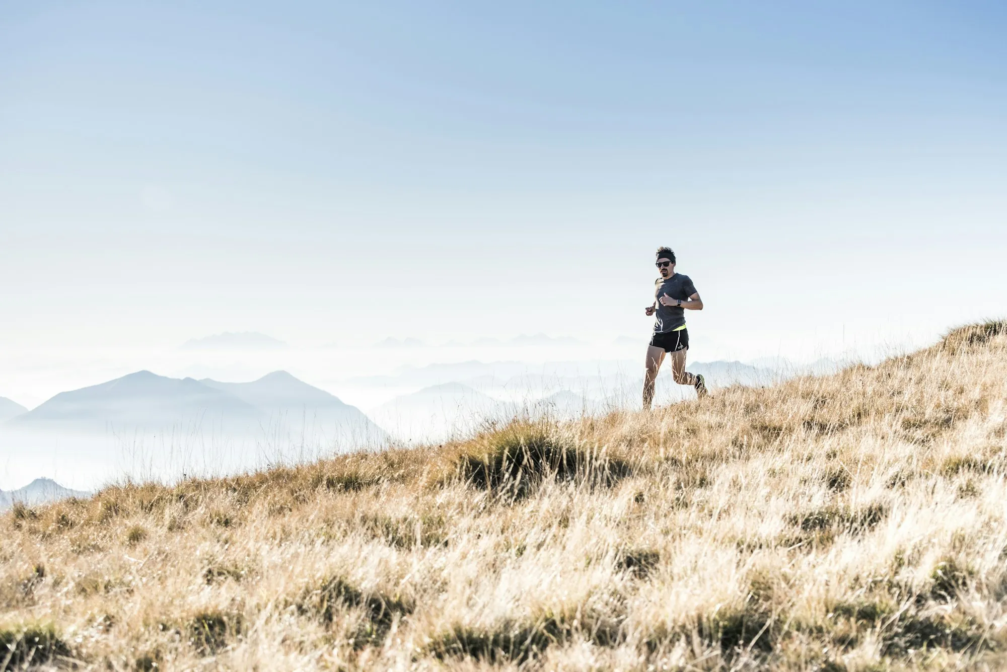 Runner on a high mountain ridge above the clouds